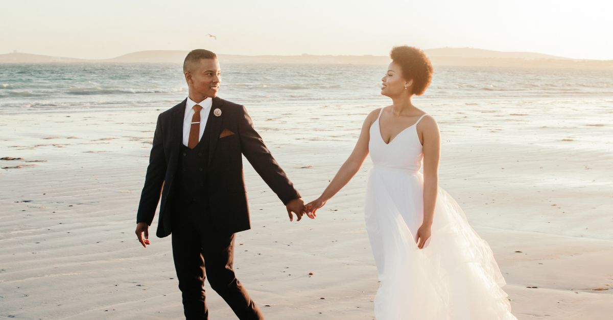 A couple who just had a Beach Wedding South Africa, walking on the beach, holding hands