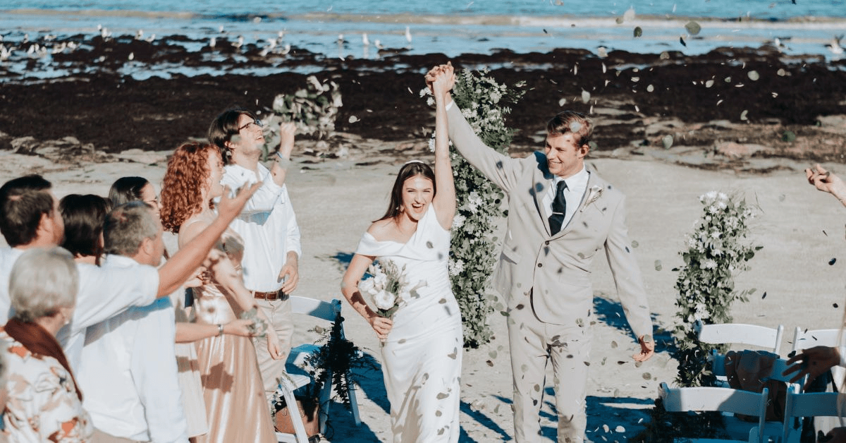Outdoor wedding ceremony at Blue Bay Lodge with newlyweds celebrating by the seaside with their guests