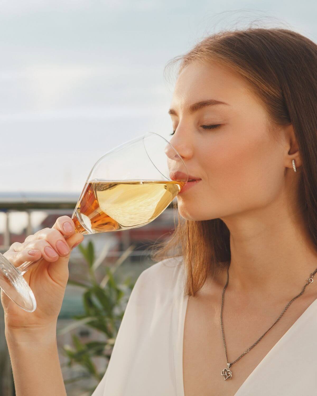 A lady drinking a glass of white wine